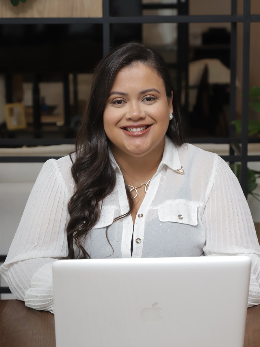 Flávia Santos em atendimento online, sorrindo em frente ao notebook